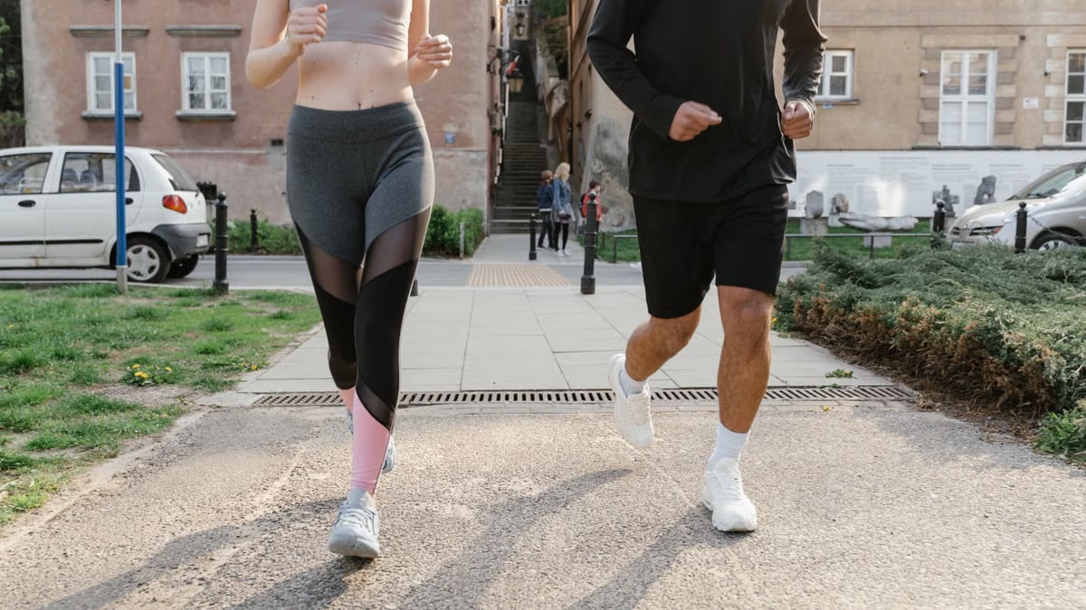 Fit couple jogging together on an urban sidewalk in sportswear.